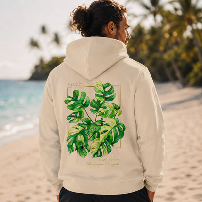Homme de dos portant le hoodie Signature beige en coton bio de la marque Viror, avec une illustration botanique de Rhaphidophora Tetrasperma Variegata sur fond de plage tropicale.